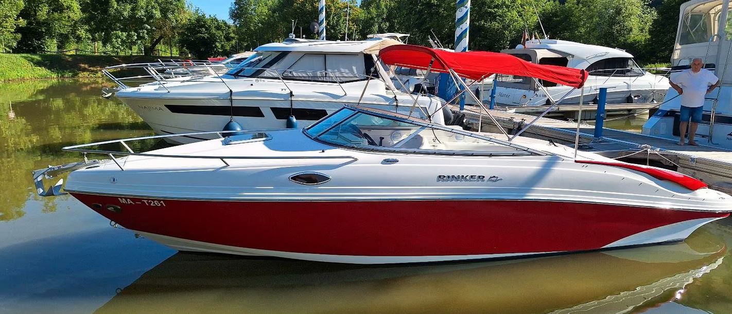 Rinker Captiva 246 mit rotem Bimini passend zu den roten Farbstreifen des Bootes von Backbord gesehen