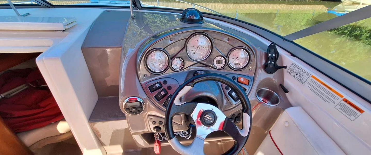 Rinker Captiva 246 mit rotem Bimini passend zu den roten Farbstreifen des Bootes, Steuerstand