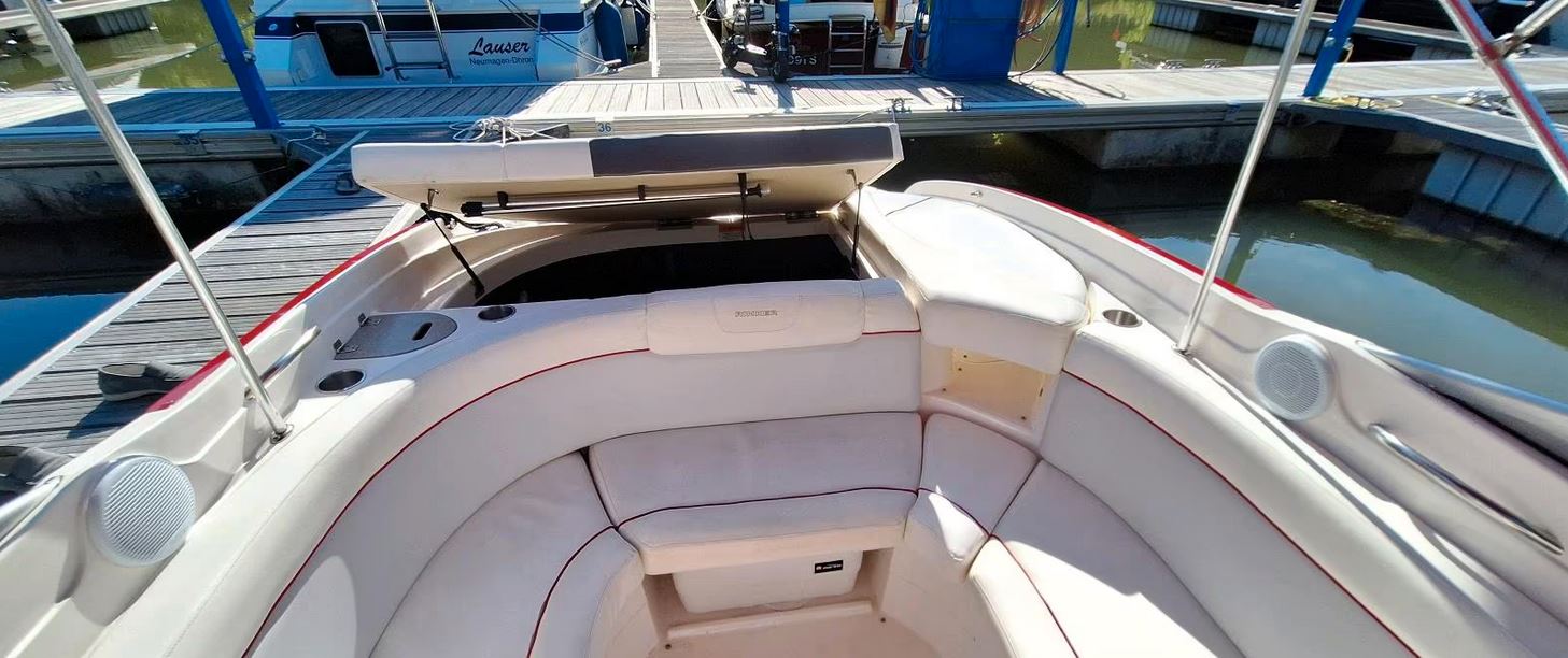 Rinker Captiva 246 mit rotem Bimini passend zu den roten Farbstreifen des Bootes, Blick Richtung Heck mit offener Klappe
