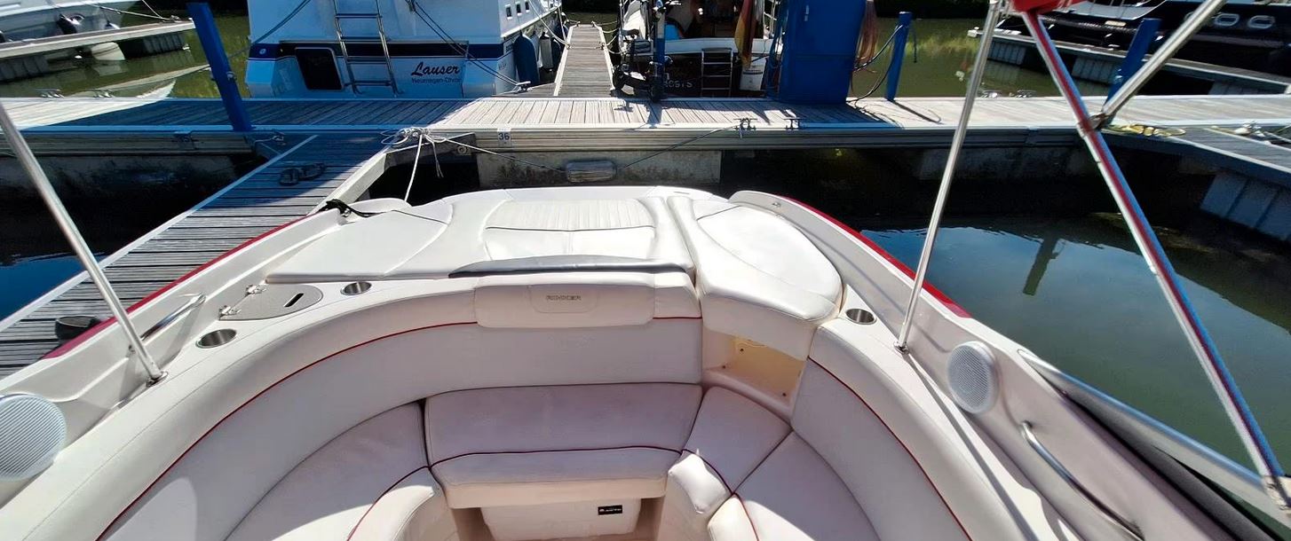 Rinker Captiva 246 mit rotem Bimini passend zu den roten Farbstreifen des Bootes, Blick Richtung Heck mit geschlossener Klappe