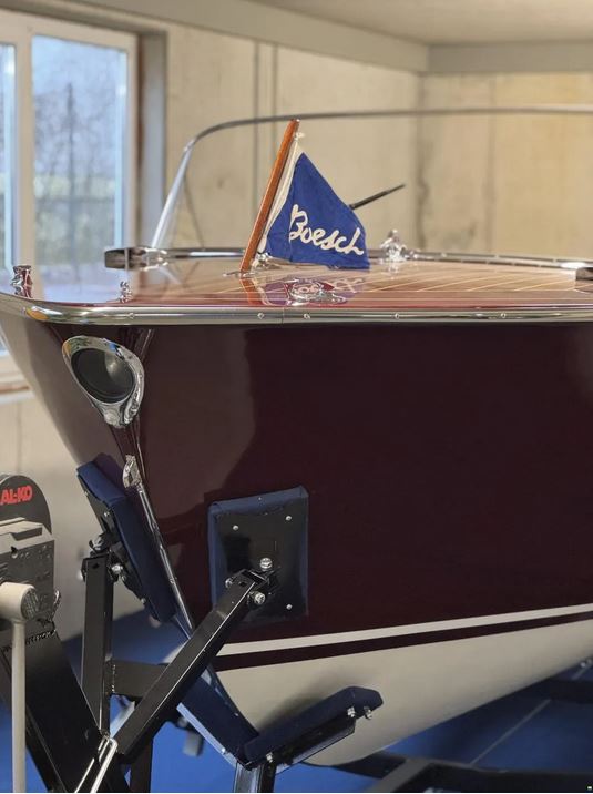 Gebrauchter Sportboot-Klassiker der Firma Boesch auf dem Trailer - Die Fahne von Boesch im Vordergrund