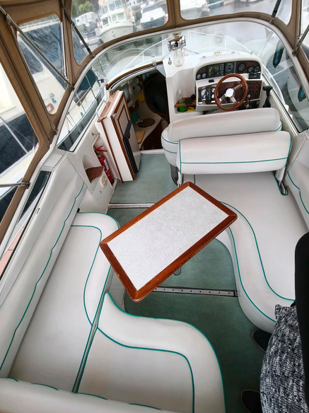 Motoryacht Nordan 7800 - Blick auf das gesamte Interieur unter der Persenning, links und vorne: Sitzgruppe, dahinter rechts der Steuerstand und links der Abgang ins Bootsinnere.